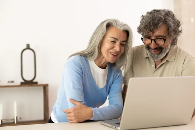 A couple at home reading something together on a laptop