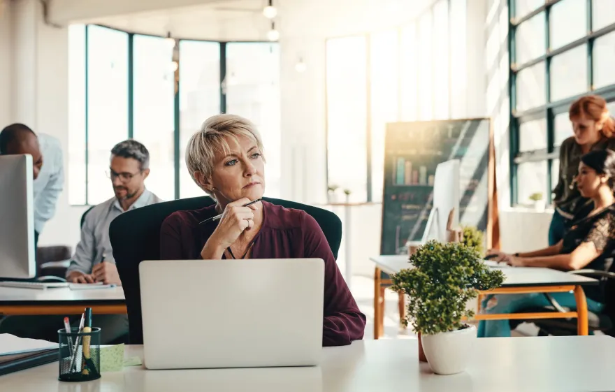 A woman pausing to think at her own laptop