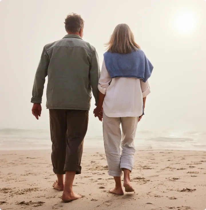 A couple walking along the shoreline at dusk
