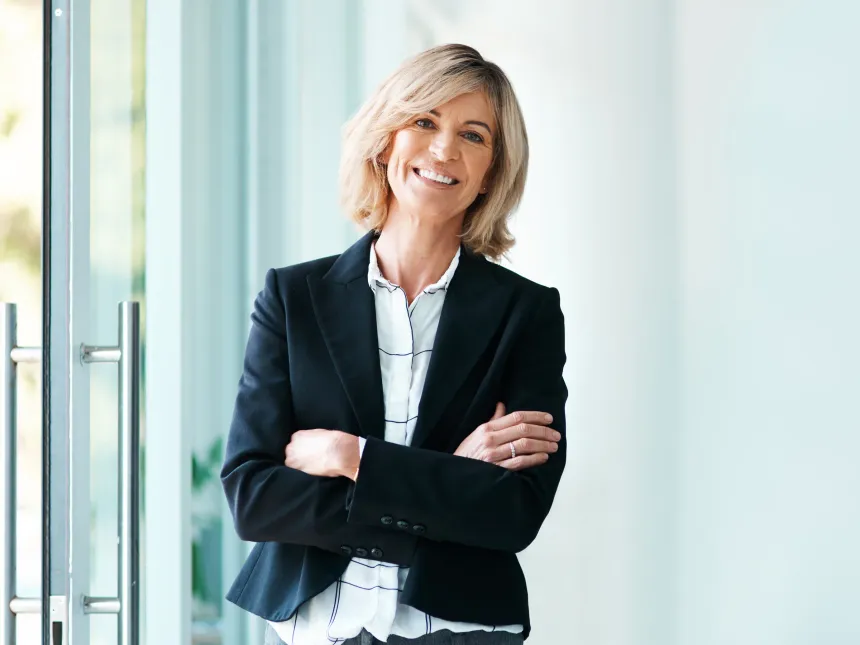 A smiling woman standing with her arms folded in a bright office
